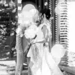 Jeunes mariés chauve et brune s'embrassant tendrement sous une pluie de bulles, bouquet de mariée rustique.