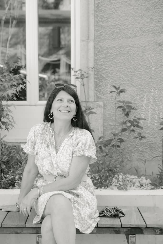 Femme souriante en robe fleurie en noir et blanc Femme souriante en robe fleurie assise sur un banc, portrait noir et blanc.